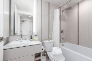 a white bathroom with a sink and a toilet and a tub at 1 BR plus Ent District,MTCC,Jays in Toronto