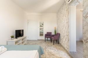 a bedroom with a bed and two chairs and a tv at Vila Martina in Novalja
