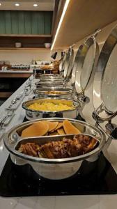 a row of dishes of food on a counter in a kitchen at Airport NH Skye Suites Hotel Terminal 3, Delhi International Airport With - Free Airport Pickup in New Delhi