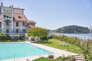 a large house with a swimming pool next to the water at Silken Gran Hotel del Sella in Ribadesella
