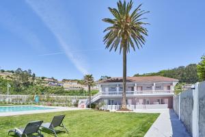 a house with a palm tree and a swimming pool at Silken Gran Hotel del Sella in Ribadesella