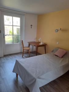a bedroom with a bed and a table and a window at Hôtellerie Abbaye Port du Salut in Entrammes +7 photos
