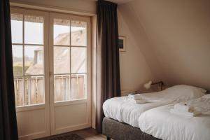 a bedroom with two beds and a large window at Dutchen Waddenduyn in Den Burg