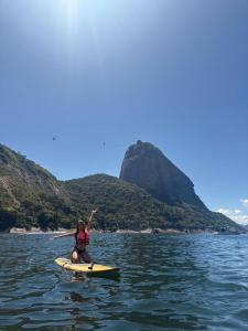 Eine Frau paddelt mit einem Paddleboard im Wasser. in der Unterkunft Quatronos in Rio de Janeiro