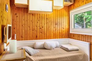 a bedroom with wood paneling and a bed with a window at Elfenwinkel am See in Gartow