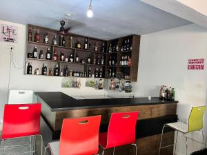 a bar with red chairs and bottles of alcohol at Esthemers Royal Hotel in Brunkum