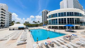 a swimming pool in front of a building with lounge chairs at SeaStays Apartments in Miami Beach
