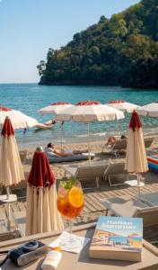 a table with a drink on a beach with umbrellas at Hotel Sant'Andrea in Santa Margherita Ligure