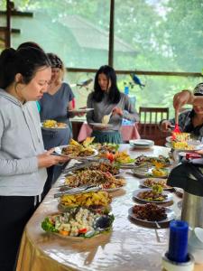 a group of people standing around a table with plates of food at Dorado Lodge in Manú