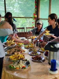 a group of people standing around a table with plates of food at Dorado Lodge in Manú