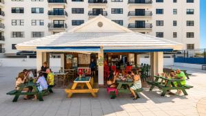 a group of people sitting at tables under a pavilion at SeaStays Apartments in Miami Beach
