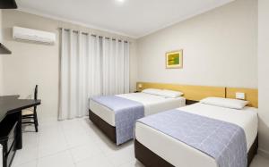 a hotel room with two beds and a desk at Bristol Exceler Campo Grande in Campo Grande