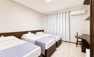a hotel room with three beds and a desk at Bristol Exceler Campo Grande in Campo Grande