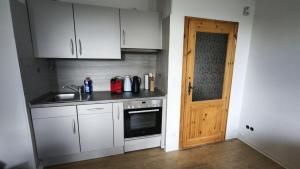 a kitchen with white cabinets and a wooden door at HochDrei - Hahnenklee in Goslar