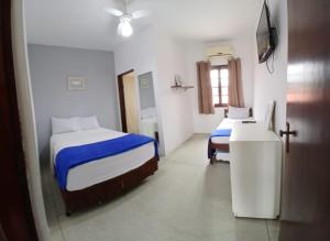 a hotel room with two beds and a window at Zaya Mar Pousada in Bertioga