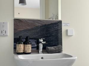 a bathroom sink with two bottles of wine on it at Auch - Trail Cabins in Bridge of Orchy