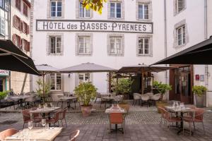 an outdoor restaurant with tables and umbrellas in front of a building at Hôtel des Basses Pyrénées - Bayonne in Bayonne