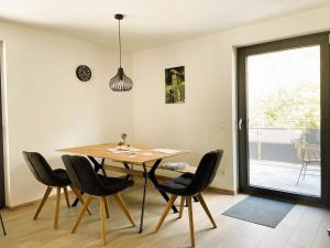 a dining room with a wooden table and black chairs at Apartment Wendehals in Vogtsburg