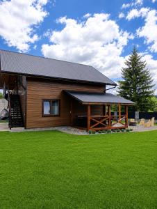 a log cabin with a green lawn in front of it at Гостинний двір in Vorokhta