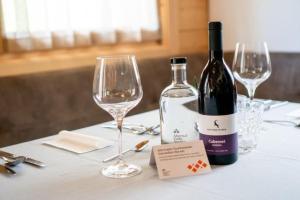 a bottle of wine sitting on a table with glasses at Chalet am Zirm in Riobianco