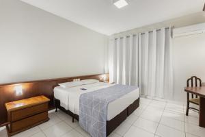 a bedroom with a bed and a table in a room at Bristol Exceler Campo Grande in Campo Grande