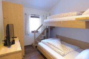 a room with three bunk beds and a television at Ausserhof Hütte mit Sauna Südtirol in Riobianco