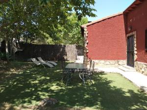 a table and chairs in a yard next to a building at Casa Rural en El Burguillo - Puerto Pez in Las Cruceras +5 photos