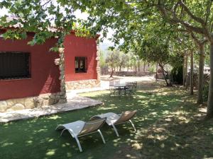 two chairs sitting under a tree next to a building at Casa Rural en El Burguillo - Puerto Pez in Las Cruceras