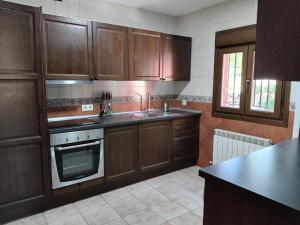 a kitchen with wooden cabinets and a sink and a stove at Casa Rural en El Burguillo - Puerto Pez in Las Cruceras