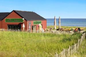 a red building on the beach next to the ocean at 8965-Allingabro-Hasselvej-3 in Skovgårde +25 photos