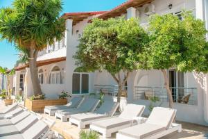 a row of chaise lounge chairs in front of a building at Newquay beach club in Kavos