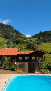 a house with a swimming pool in front of a mountain at Sítio Espírito Santo in Paraisópolis