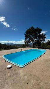 a blue swimming pool with a tree in the background at Sítio Espírito Santo in Paraisópolis