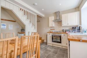a kitchen with white cabinets and a table and chairs at Delfryn in Tenby