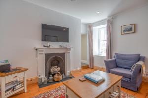 a living room with a fireplace and a blue chair at Delfryn in Tenby