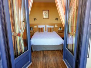 a small bedroom with a bed and two windows at Hotel Restaurant La Clairiere in Chambon-sur-Dolore