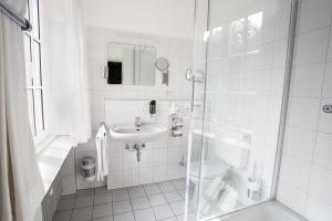 ein weißes Badezimmer mit Toilette und Waschbecken in der Unterkunft Stadthotel Jülich in Jülich + 16 Fotos