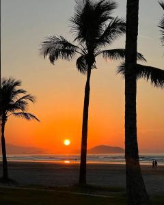 a sunset on the beach with palm trees at Zaya Mar Pousada in Bertioga +22 photos
