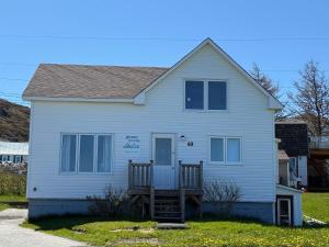a white house with a porch and a stairway in front at Whimsea Cottage in Twillingate