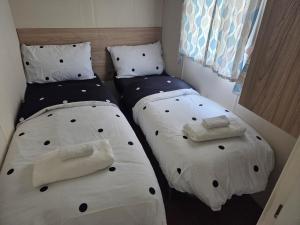 two beds in a small room with white sheets and pillows at Awesome Static Caravan Holiday Home in Great Billing