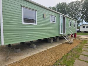 a green tiny house on display in a yard at Awesome Static Caravan Holiday Home in Great Billing