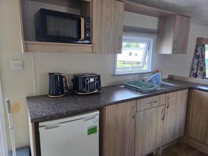 a small kitchen with a sink and a microwave at Awesome Static Caravan Holiday Home in Great Billing +5 photos