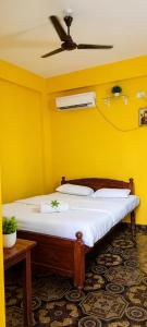 a bed in a yellow room with a ceiling fan at Samhen guest house in Majorda