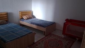 a room with two beds and a tv and a rug at appart CRISTIANA 3 Midoun in Midoun