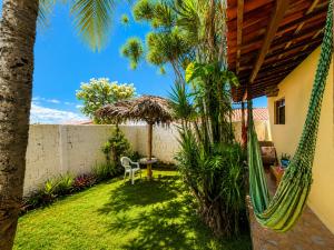 a hammock in the backyard of a house with palm trees at Chalé Rosani in Pipa