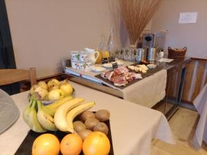 a table with bananas oranges and other fruits on it at Hotel Restaurant La Clairiere in Chambon-sur-Dolore