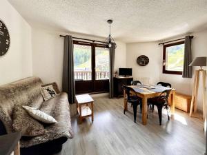 a living room with a couch and a dining room table at Studio rénové cœur de station, skis aux pieds - FR-1-322-323 in Les Orres