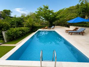 a swimming pool with two chairs and an umbrella at Light Blue Villa in Tepus +6 photos