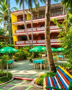 a hotel with tables and chairs and umbrellas at Samhen guest house in Majorda