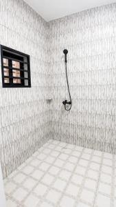 a bathroom with a shower in a white tiled wall at Grand Studio Meublé à Lomé in Komé